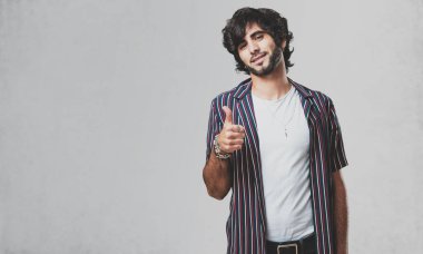 Genç yakışıklı adam neşeli ve heyecanlı, gülümseyerek onu başparmak, başarı ve onay, kavram yükselterek ok ve jest
