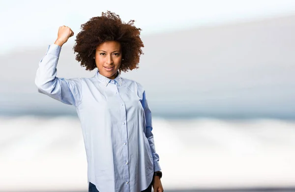 Jonge Zwarte Vrouw Blauw Shirt Doen Sterke Gebaar Onscherpe Achtergrond — Stockfoto