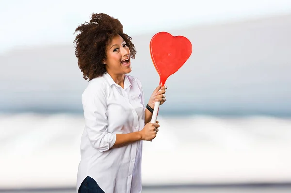 young black woman eating a big lollipop on blurred background