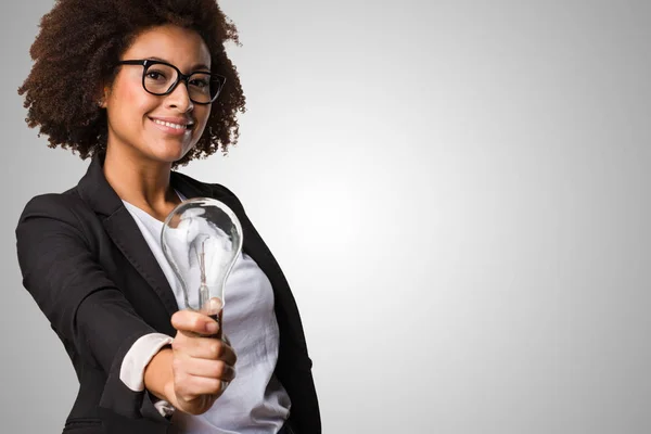 Schwarze Geschäftsfrau Mit Einer Glühbirne Auf Grauem Hintergrund — Stockfoto