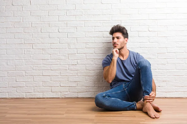 Jovem Homem Natural Sentar Piso Madeira Duvidoso Confuso Pensando Uma — Fotografia de Stock