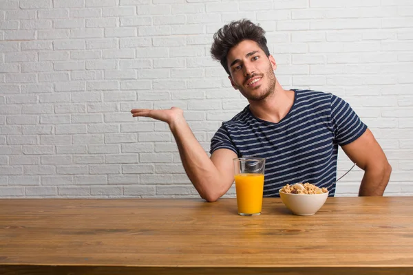 Joven Hombre Guapo Natural Sentado Una Mesa Sosteniendo Algo Con — Foto de Stock