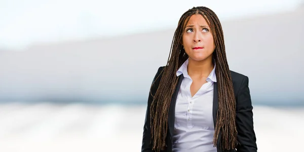 Portrait of a young black business woman doubting and confused, thinking of an idea or worried about something