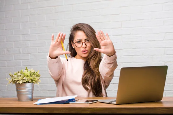 Ciddi ve kararlı masada oturan genç öğrenci latin kadın portresi