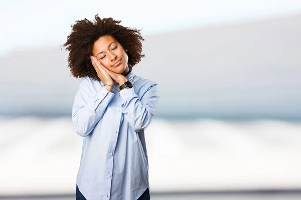 young black woman in blue shirt sleeping on blurred background
