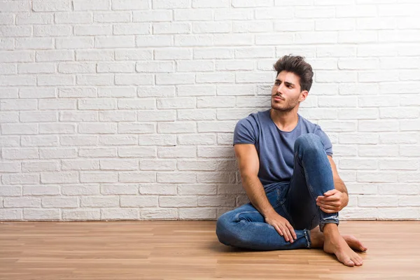 Doğal delikanlı oturup şüphen ve karıştı, bir ahşap zemin üzerinde bir fikir ya da bir şey hakkında endişeli