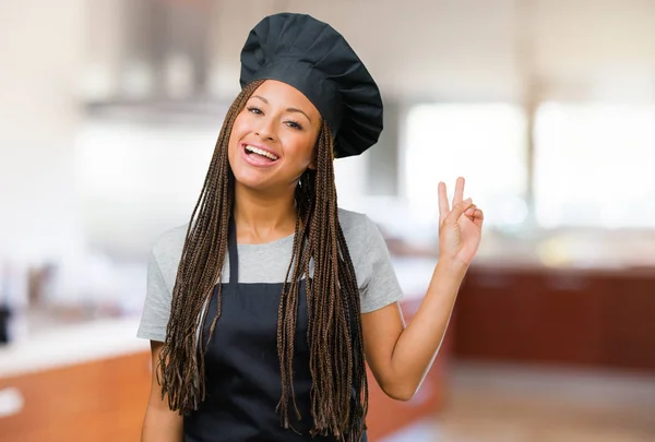 Portrait of a young black baker woman fun and happy, positive and natural, makes a gesture of victory, peace concept