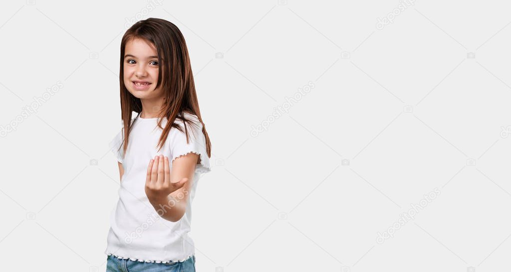 Full body little girl inviting to come, confident and smiling making a gesture with hand, being positive and friendly