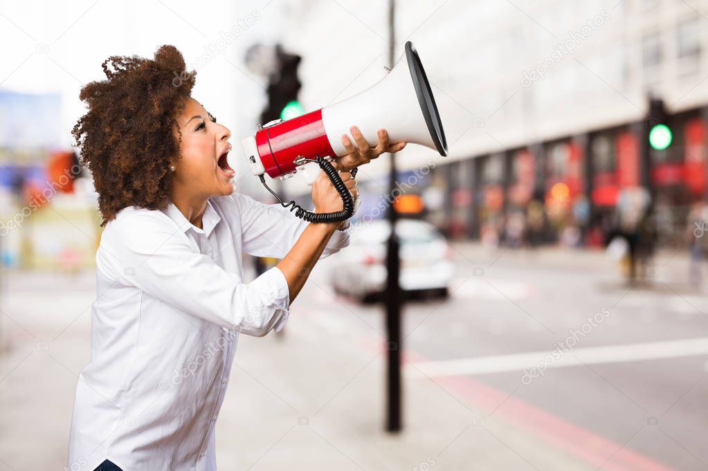 young black woman shouting on megaphone on blurred background