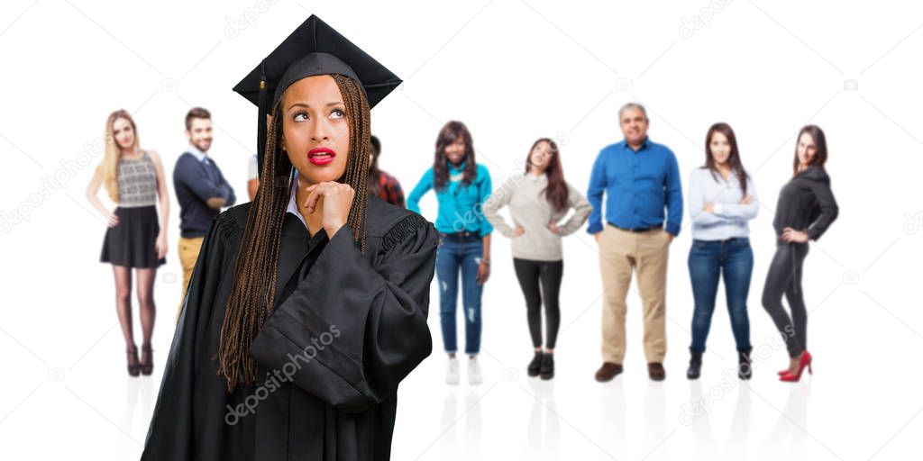 Young graduated black woman wearing braids thinking and looking up, confused about an idea, would be trying to find a solution