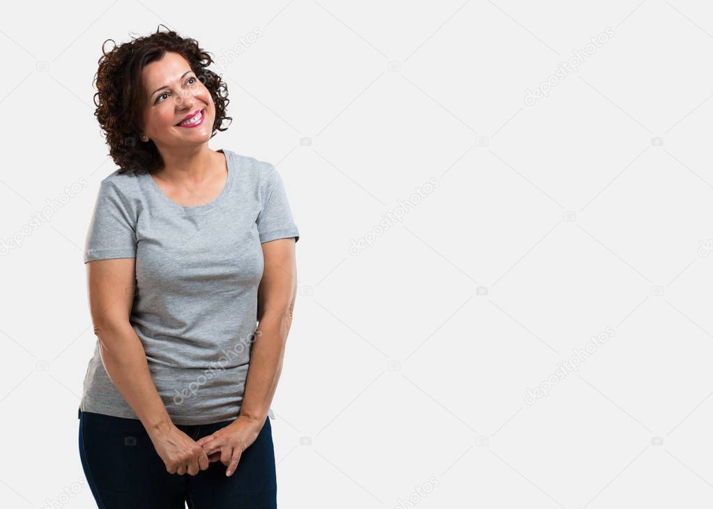 Middle aged woman looking up, thinking of something fun and having an idea, concept of imagination, happy and excited