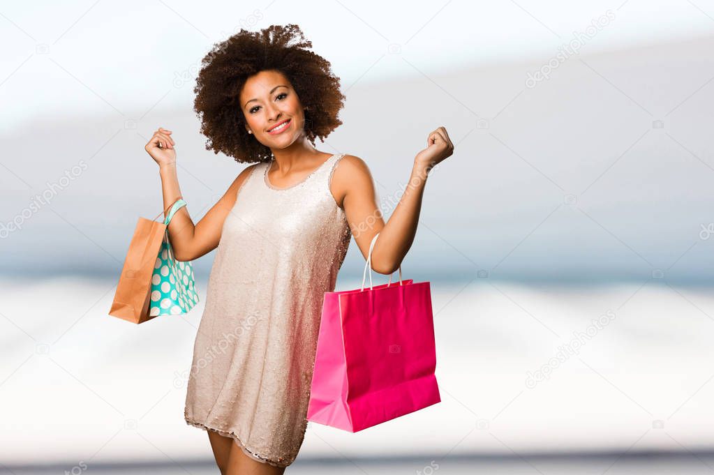 young black woman holding shopping bags on blurred background