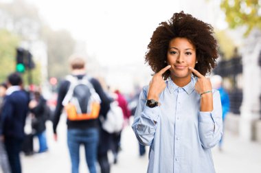 Genç siyah kadın ağzını bulanık arka plan üzerine işaret