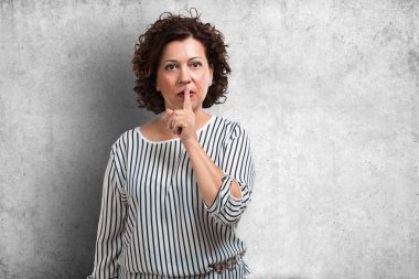 Bir sırrı saklamak veya soran sessizlik, ciddi bir yüz, itaat kavramı için orta yaşlı kadın