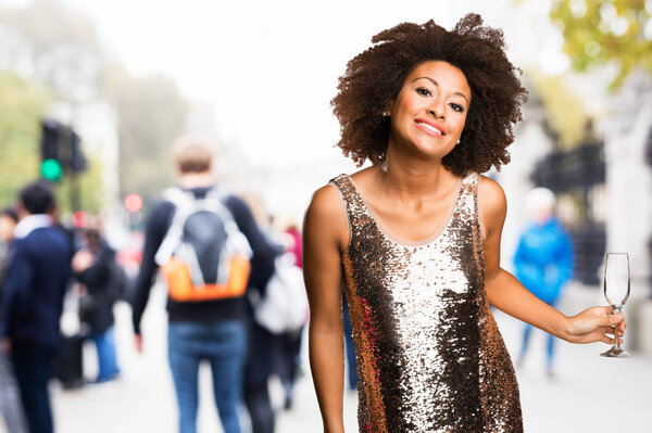 young black woman in stylish dress holding a cocktail glass on blurred background