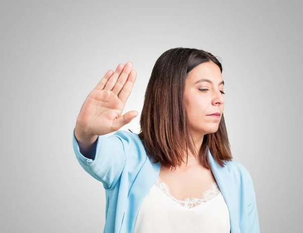 Middle aged woman serious and determined, putting hand in front, stop gesture, deny concept