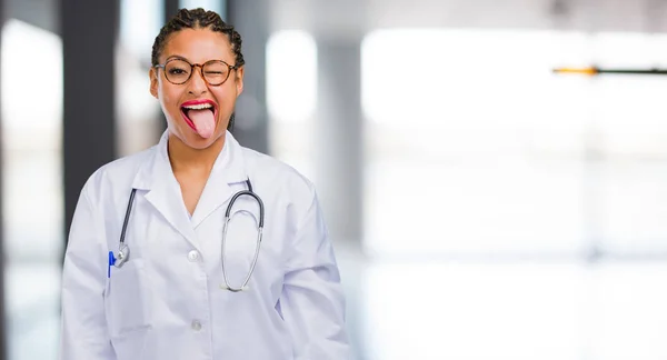 Portrait of a young black doctor woman expression of confidence and emotion, fun and friendly, showing tongue as a sign of play or fun