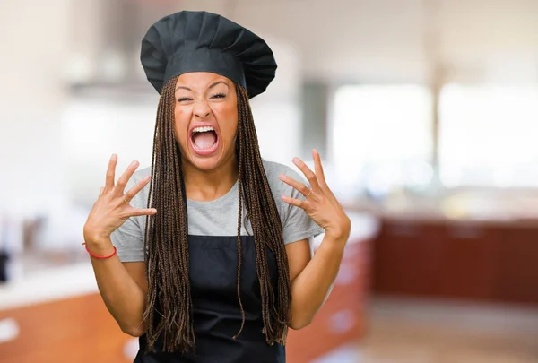 Portrait of a young black baker woman very angry and upset, very tense, screaming furious, negative and crazy
