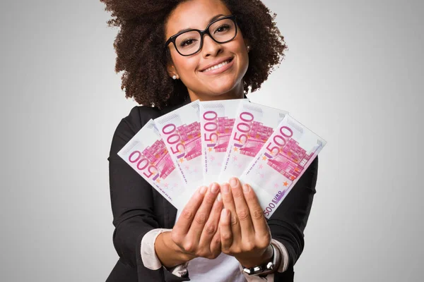 black business woman holding bills on gray background