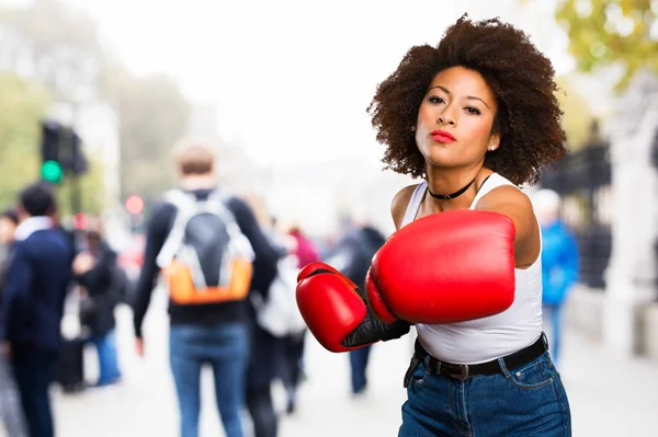 young black woman using boxing gloves on blurred background