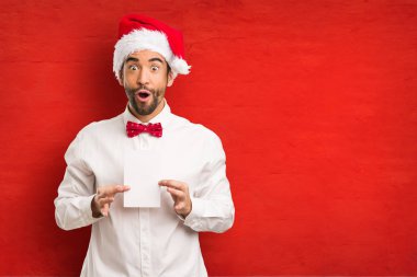 Noel gününde Noel Baba şapkası giyen genç adam