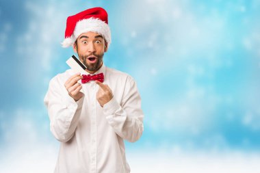 Noel gününde Noel Baba şapkası giyen genç adam