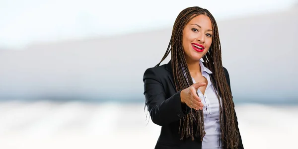 Portrait of a young black business woman reaching out to greet someone or gesturing to help, happy and excited