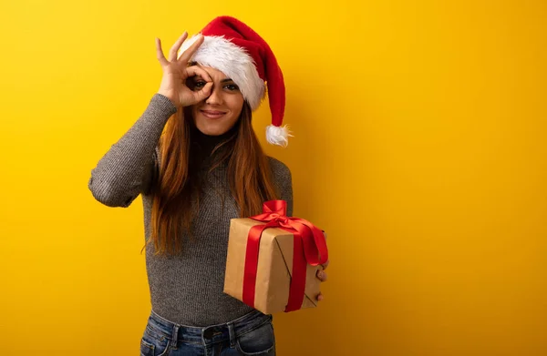 Young Pretty Woman Holding Gift Confident Doing Gesture Eye — Stock Photo, Image