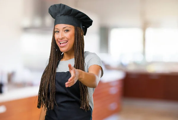 Portrait of a young black baker woman reaching out to greet someone or gesturing to help, happy and excited