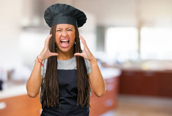 Portrait of a young black baker woman screaming angry, expression of madness and mental instability, open mouth and half-opened eyes, madness concept