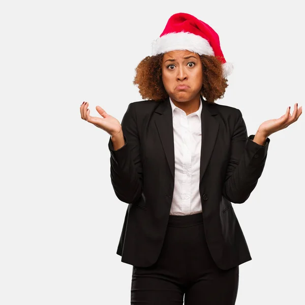 Young Business Black Woman Wearing Chirstmas Santa Hat Doubting Shrugging — Stock Photo, Image