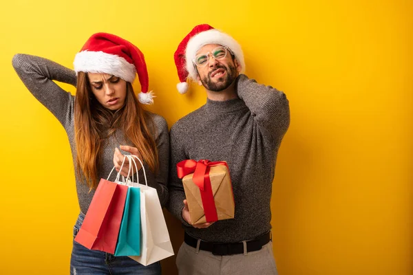 Couple or friends holding gifts and shopping bags suffering neck pain