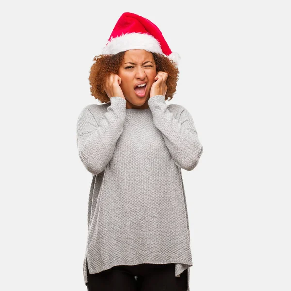 年轻的黑人妇女戴着圣诞老人的帽子 用双手覆盖耳朵 — 图库照片