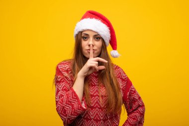 Bir sırrı saklamak veya sessizlik için soran Noel Baba şapkası giyen genç kadın