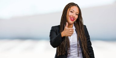 Gülümseyen ve onu başparmak, başarı ve onay, ok jest kavramı yükselterek bir genç siyah iş kadını neşeli ve heyecanlı, portresi