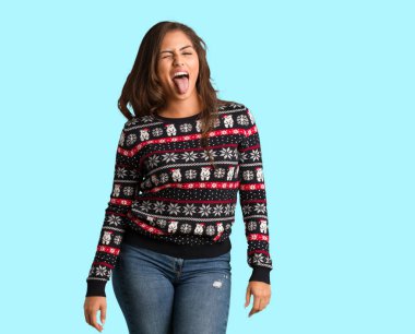 Bir Noel jersey huni giyen ve dost dilini gösteren tam vücut genç kadın
