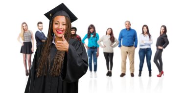 Genç gülümseyen ve onu başparmak, başarı ve onay, ok jest kavramı yükselterek örgüler neşeli ve heyecanlı, giyen siyah kadın mezun oldu.