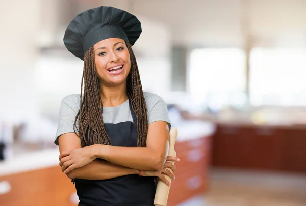 Portrait of a young black baker woman crossing his arms, smiling and happy, being confident and friendly