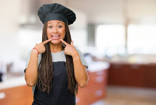 Portrait of a young black baker woman smiles, pointing mouth, concept of perfect teeth, white teeth, has a cheerful and jovial attitude