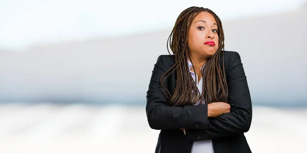 Portrait of a young black business woman doubting and shrugging shoulders, concept of indecision and insecurity, uncertain about something