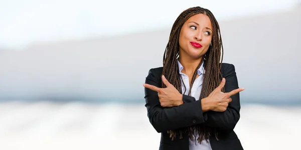 Portrait of a young black business woman confused and doubtful man, decide between two options, concept of indecision