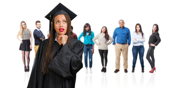 若い黒人女性のお下げと見上げる アイデアについて困惑するいると考えて着てを卒業し 解決策を見つけることを試みるだろう — ストック写真