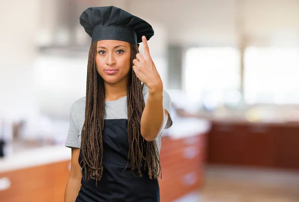 Portrait of a young black baker woman showing number one, symbol of counting, concept of mathematics, confident and cheerful