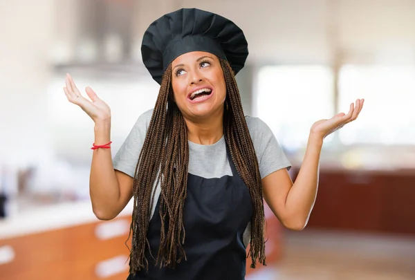 Portrait of a young black baker woman laughing and having fun, being relaxed and cheerful, feels confident and successful