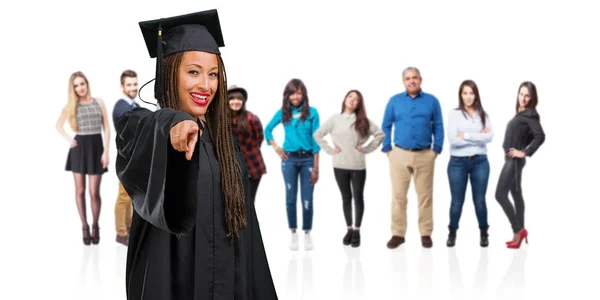 年轻毕业的黑人妇女穿着辫子开朗和微笑指向前面 — 图库照片