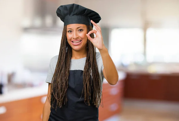 Portrait of a young black baker woman cheerful and confident doing ok gesture, excited and screaming, concept of approval and success