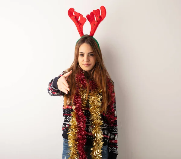 Young pretty woman wearing christmas clothes reaching out to greet someone