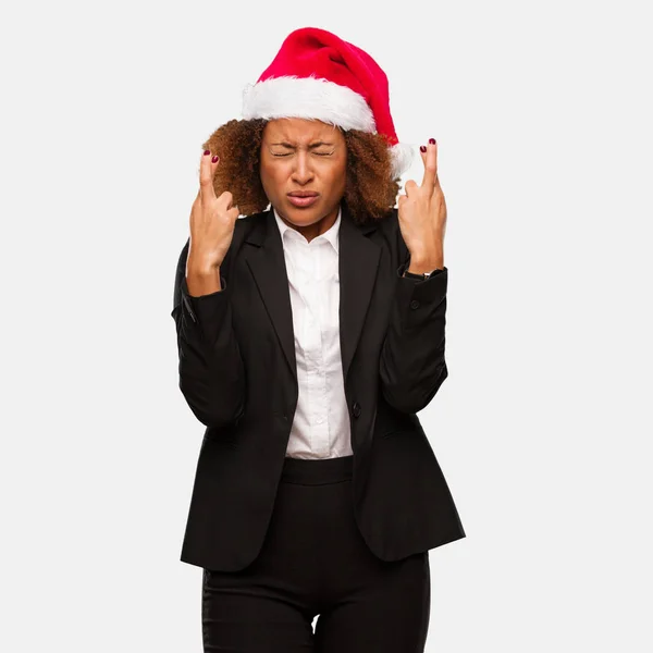 Young Business Black Woman Wearing Chirstmas Santa Hat Crossing Fingers — Stock Photo, Image