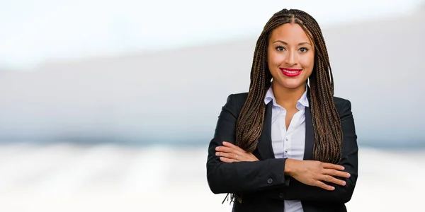 Portrait of a young black business woman crossing his arms, smiling and happy, being confident and friendly