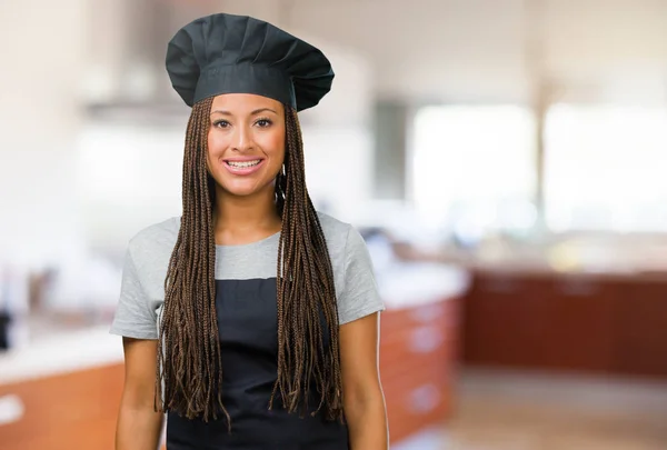 Portrait of a young black baker woman cheerful and with a big smile, confident, friendly and sincere, expressing positivity and success